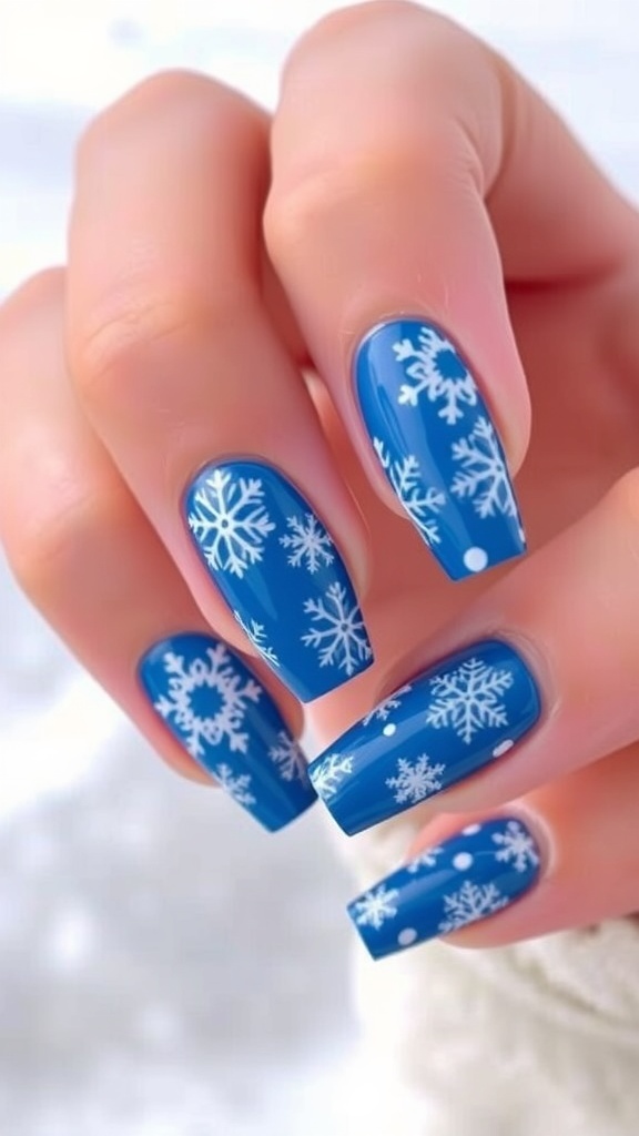 Close-up of blue Christmas nails with white snowflake designs against a snowy background.